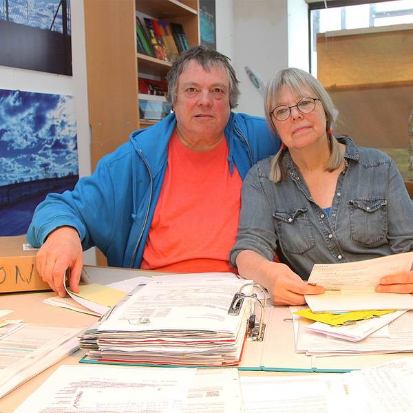 Hartwig Kausch und Silvia Kock sitzen an einem Tisch. Vor ihnen liegen Aktenordner und Papierstapel.