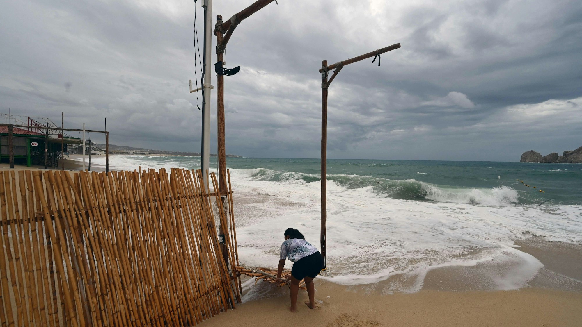 Eine Mitarbeiterin einer Strandbar baut in Mexiko einen Zaun am Strand auf.