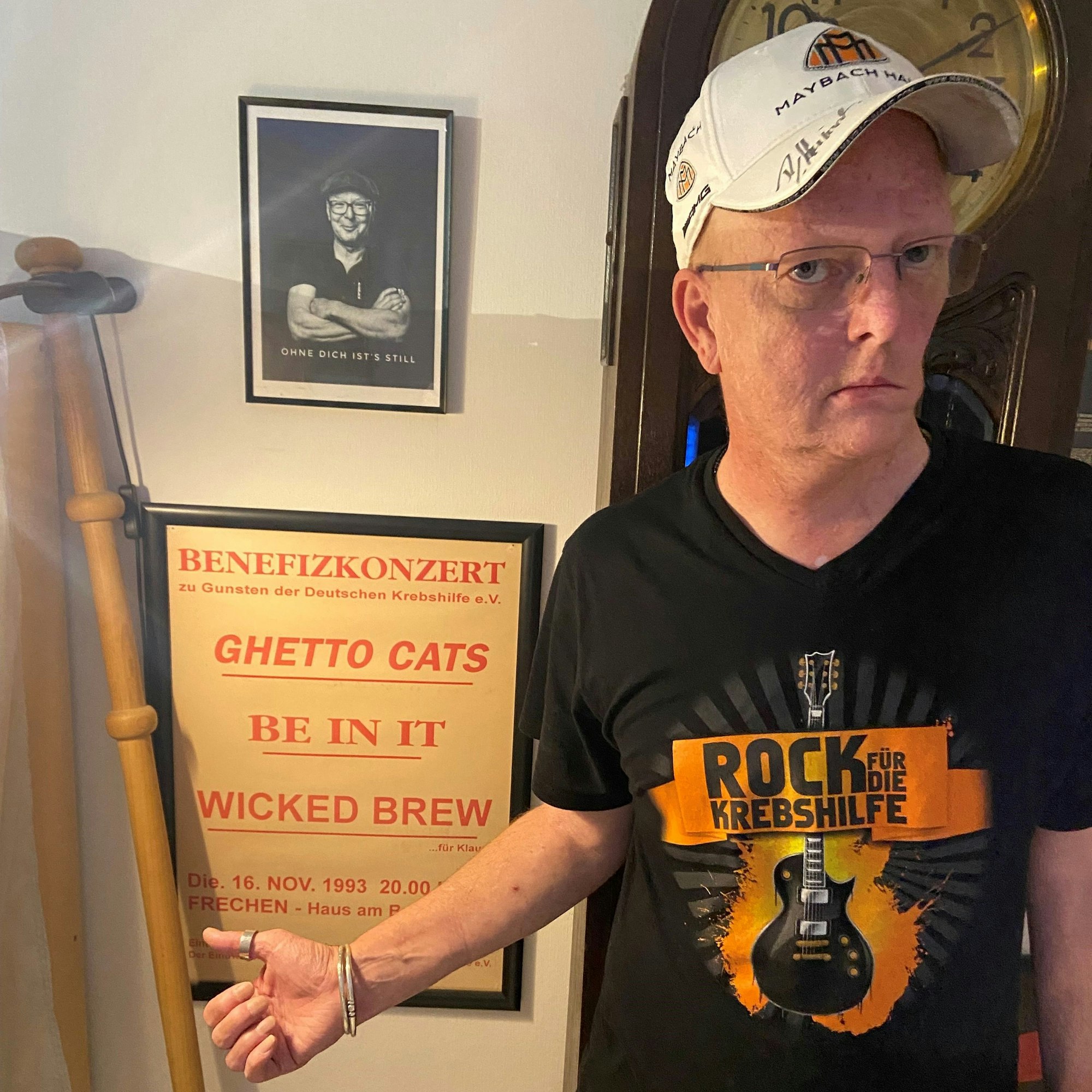 Ein Mann zeigt ein altes Plakat und ein Foto seines verstorbenen Freundes.