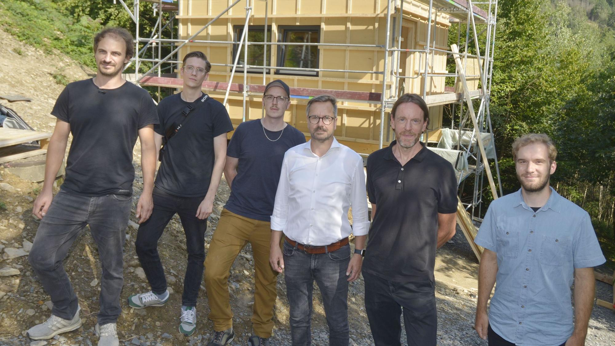 Sechs Männer stehen vor einem Häuserneubau.