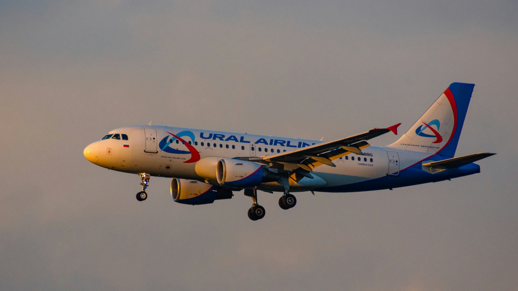 Ein Airbus A319 der russischen Fluggesellschaft Ural Airlines fliegt am Himmel. Von vorne scheint die Sonne auf das Flugzeug. (Symbolbild)