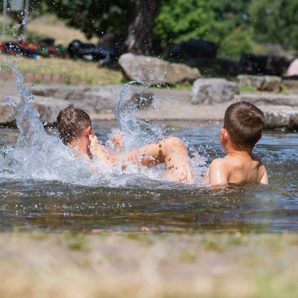 Zwei Jungs liegen im Wasser und plantschen.