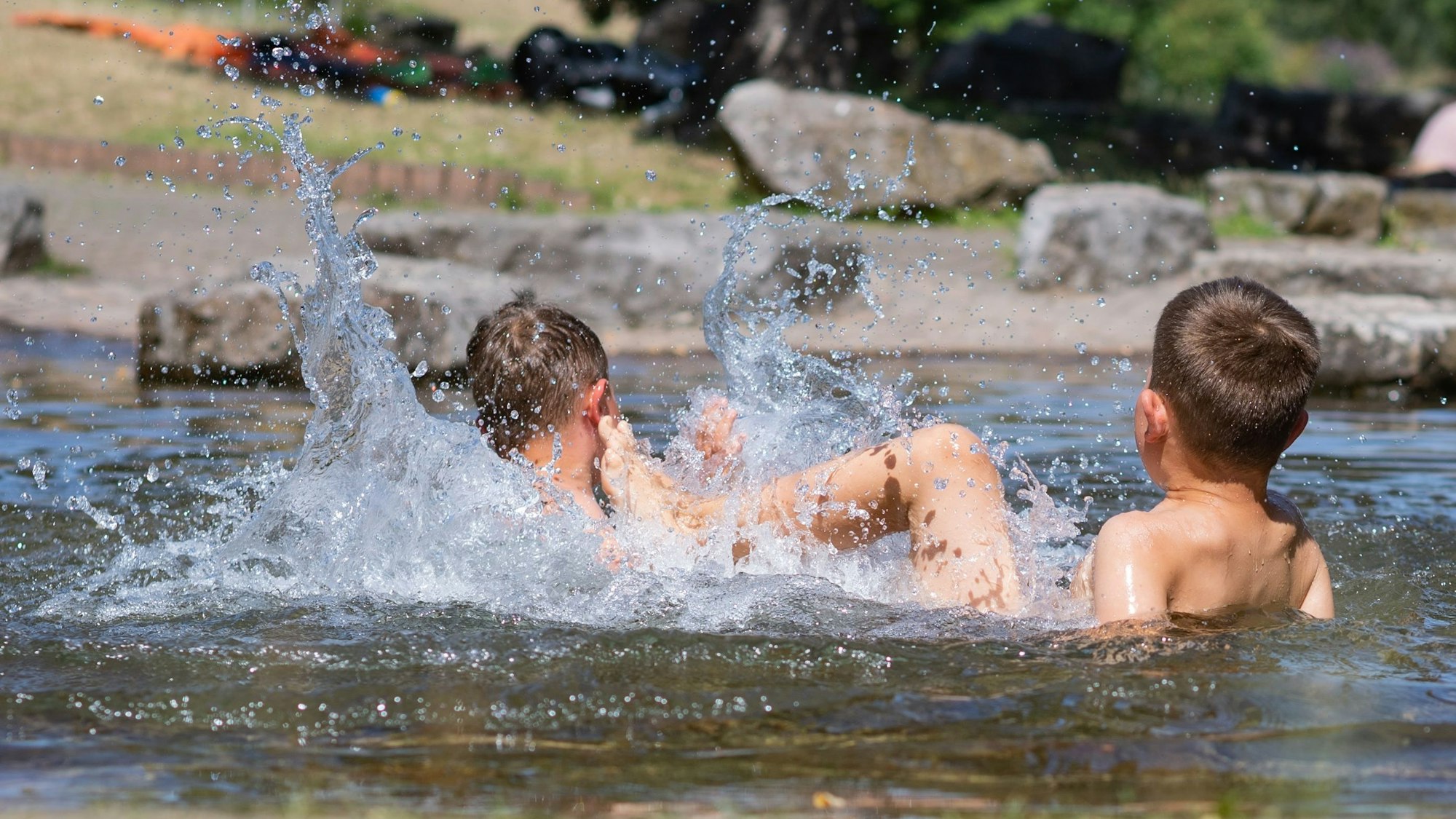 Zwei Jungs liegen im Wasser und plantschen.