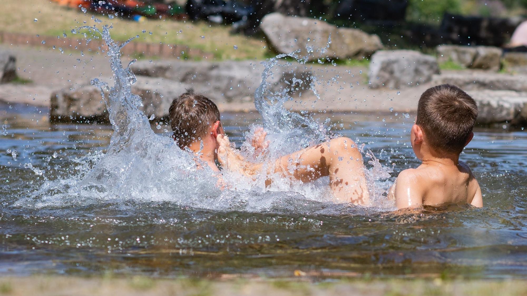 Das Bild zeigt zwei Jungs, die im Wasser planschen.