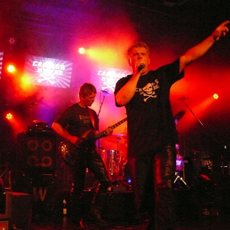Rockmusiker spielen auf einer rot ausgeleuchteten Bühne.