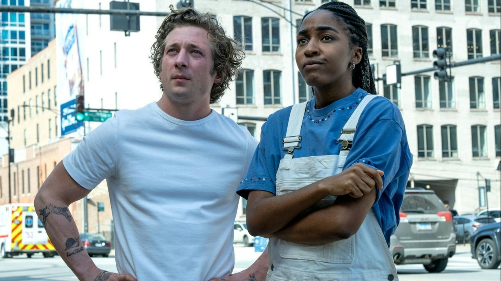 Szene aus der US-Serie „The Bear“, deren zweite Staffel jetzt auf Disney+ läuft. Man sieht die Jeremy Allen White (l.) und Ayo Edebiri an einer Straßenkreuzung in Chicago stehen, ihr neues Restaurant betrachtend.
