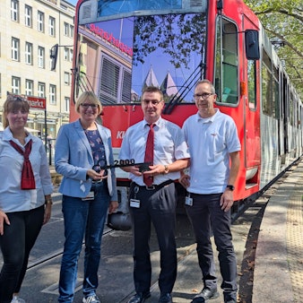 Die vier Personen stehen am Neumarkt vor einer ausrangierten Bahn. Stefanie Haaks überreicht Frank Faßbender einen Schlüssel