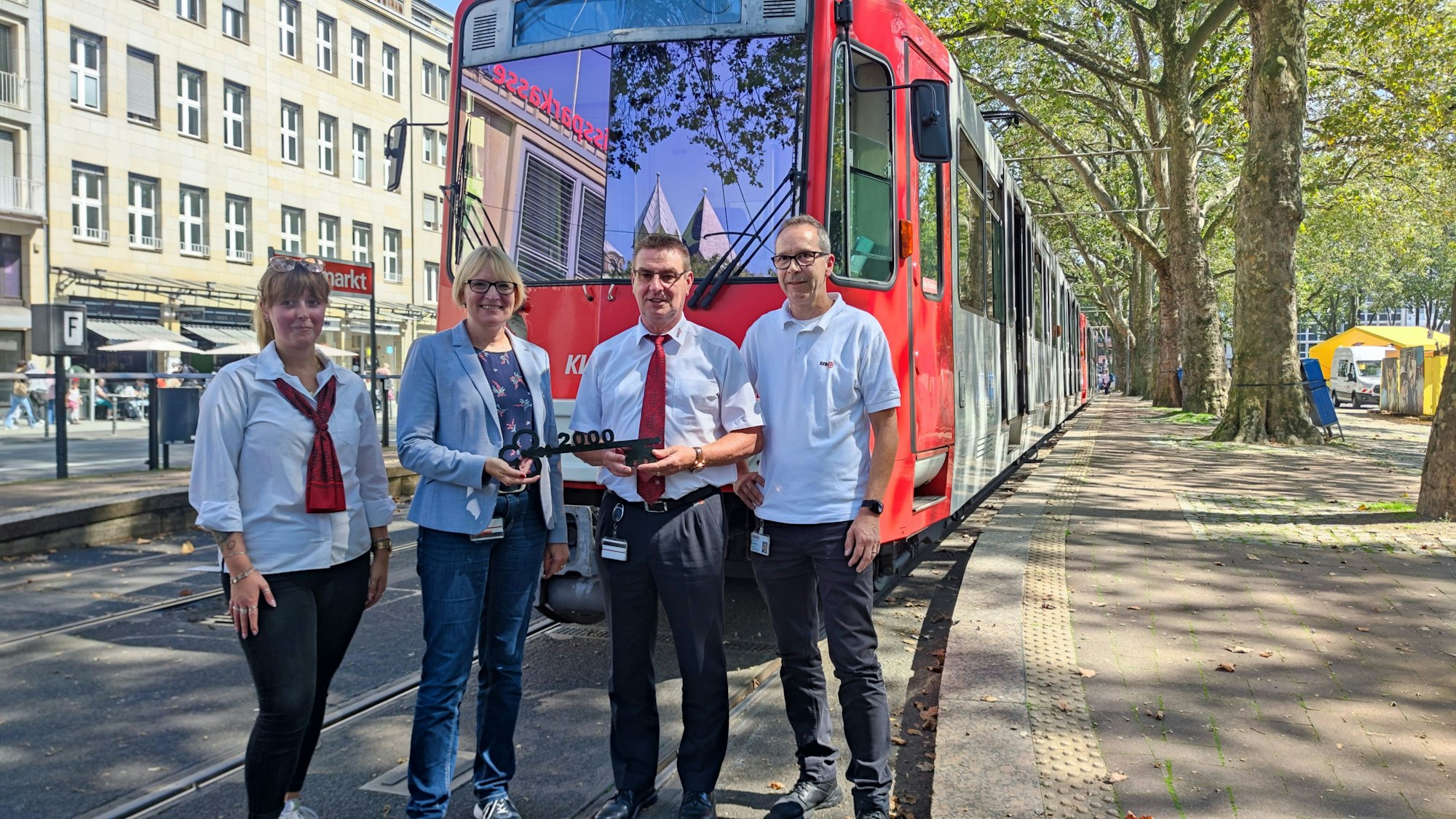 Die vier Personen stehen am Neumarkt vor einer ausrangierten Bahn. Stefanie Haaks überreicht Frank Faßbender einen Schlüssel