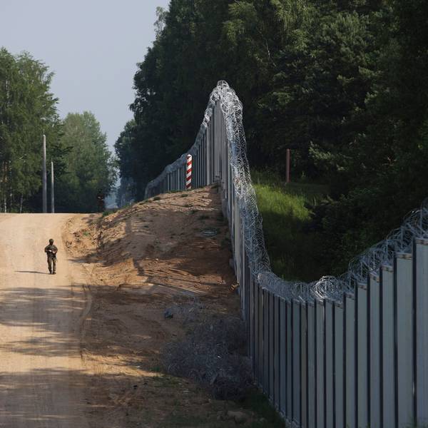 Ein polnischer Grenzschutzbeamter patrouilliert im Bereich einer errichteten Metallmauer an der Grenze zwischen Polen und Belarus, die mit Stacheldraht versehen ist.