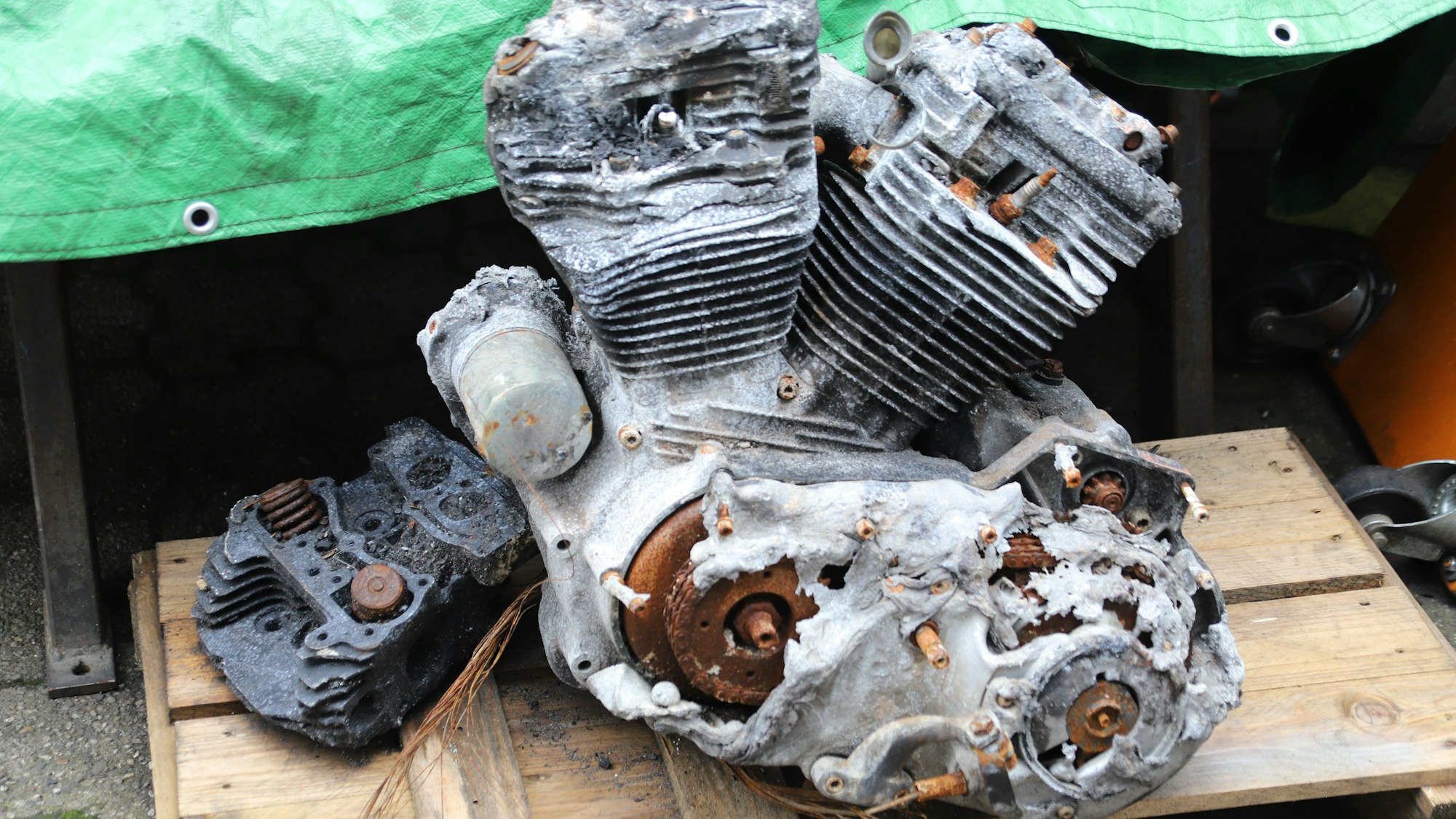 Ein weitgehend geschmolzener Motor liegt auf einer Palette.