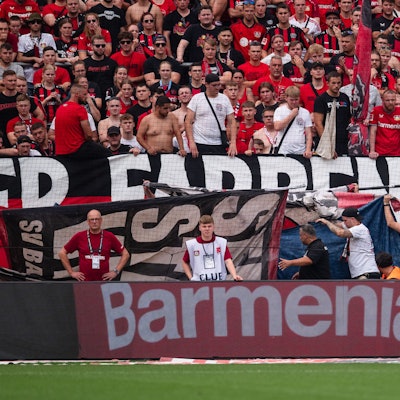 Abgeschirmt von Fan-Flaggen wird ein verletzter Zuschauer aus dem Stadion gebracht.