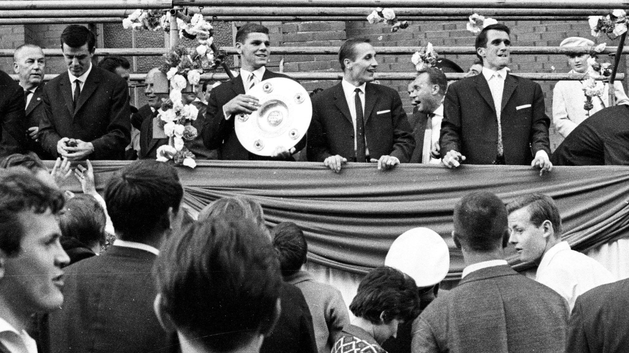 Spieler des 1. FC Köln feiern mit Fans ihren Sieg: Sie wurden 1964 in der ersten Saison der Bundesliga Deutscher Meister. Von links: Torwart Fritz Ewert, Wolfgang Weber mit der Schale, Heinz Hornig, Wolfgang Overath, Anton Regh.
