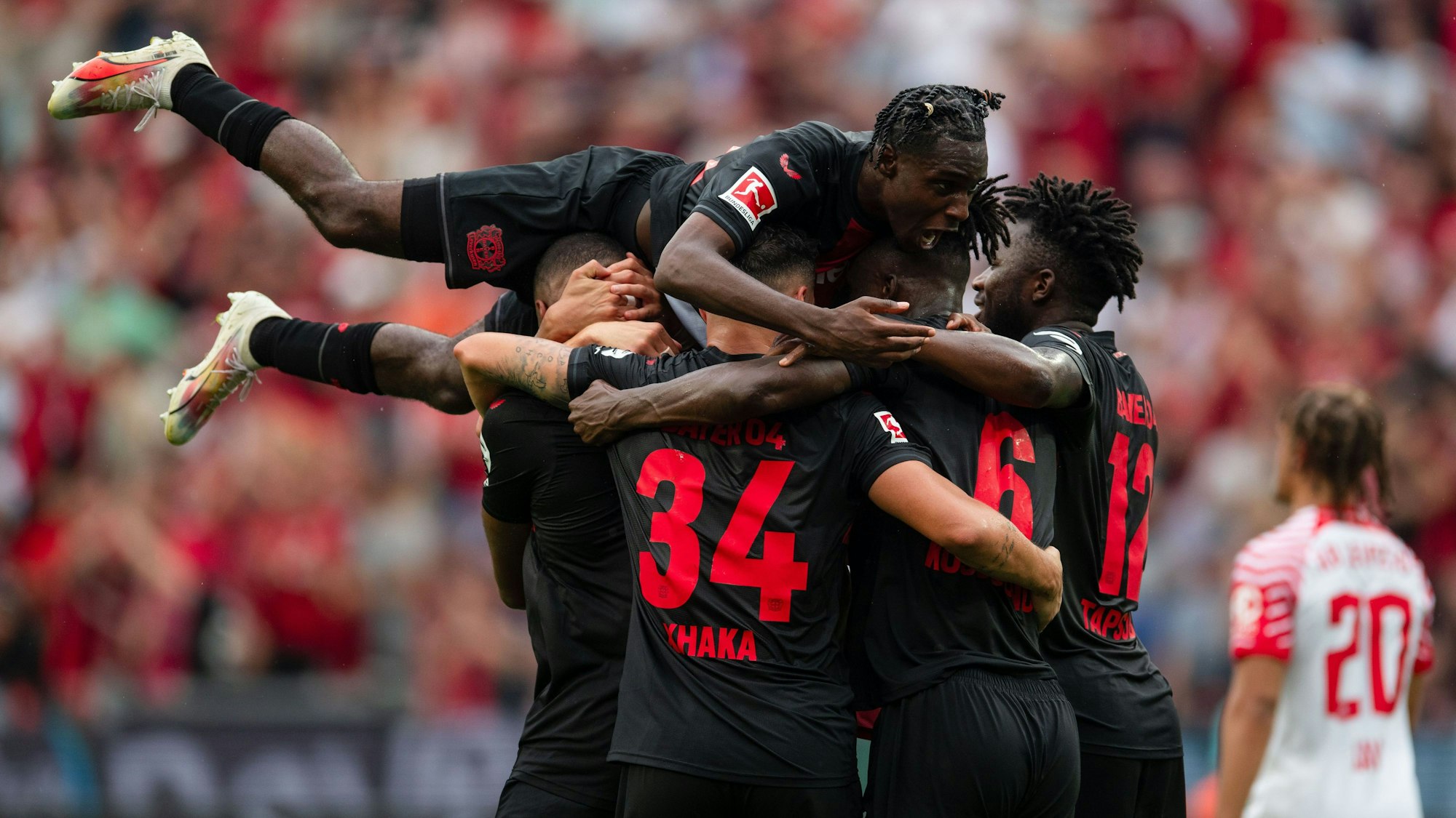 Leverkusens Jeremie Frimpong springt nach dem Treffer zur 2:0-Führung auf den Torschützen Jonathan Tah, Granit Xhaka, Odilon Kossounou und Edmond Tapsoba (v. l.).