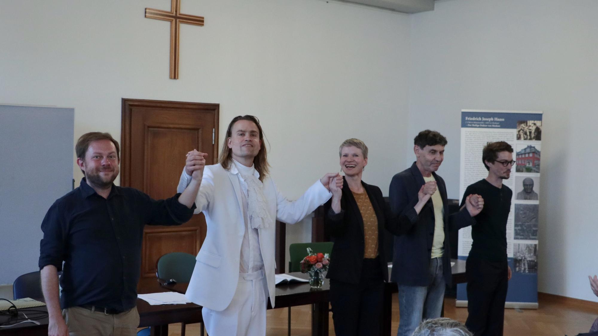 Das Bild zeigt René Michaelsen, Laurenz Leky, Juliane Pempelfort, Mark Zak und Alexander Olbrich. Sie halten sich an den Händen.
