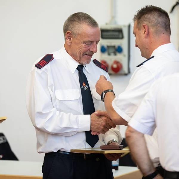 Ein Feuerwehrmann bekommt eine Ehrennadel angesteckt.