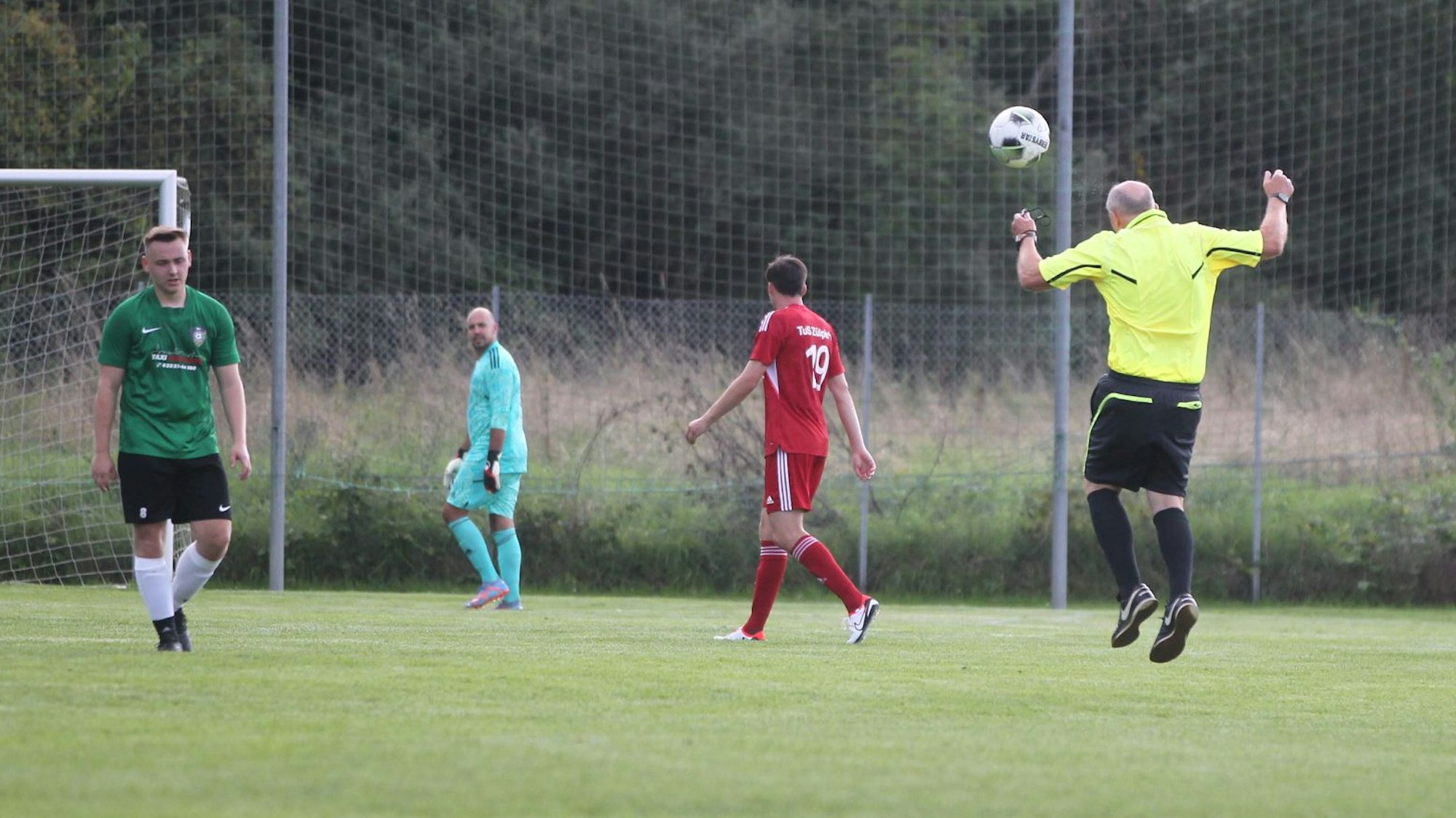 Der Schiedsrichter köpft einen Ball.