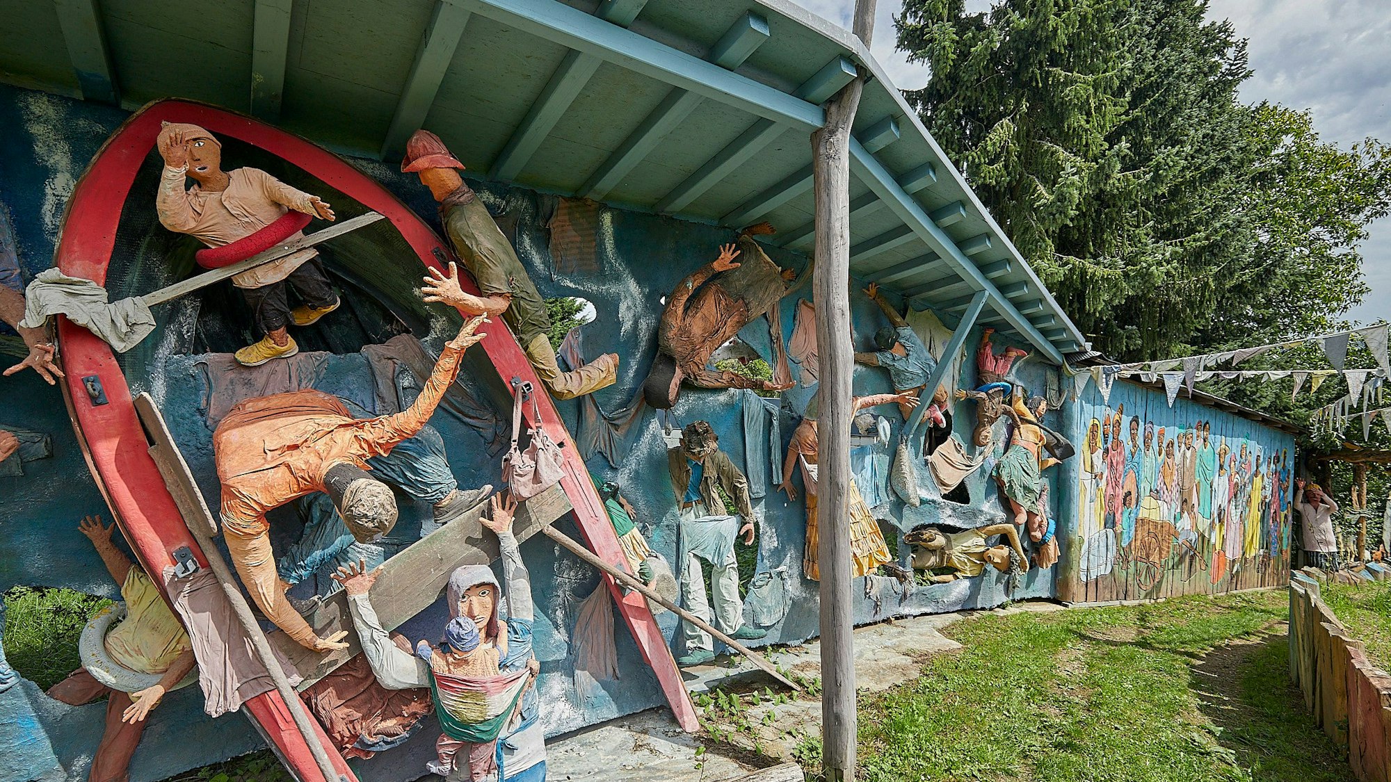 Auf dem Bild sieht man eine Skulptur eines kenternden Bootes, auf dem sich menschliche Figuren befinden.
