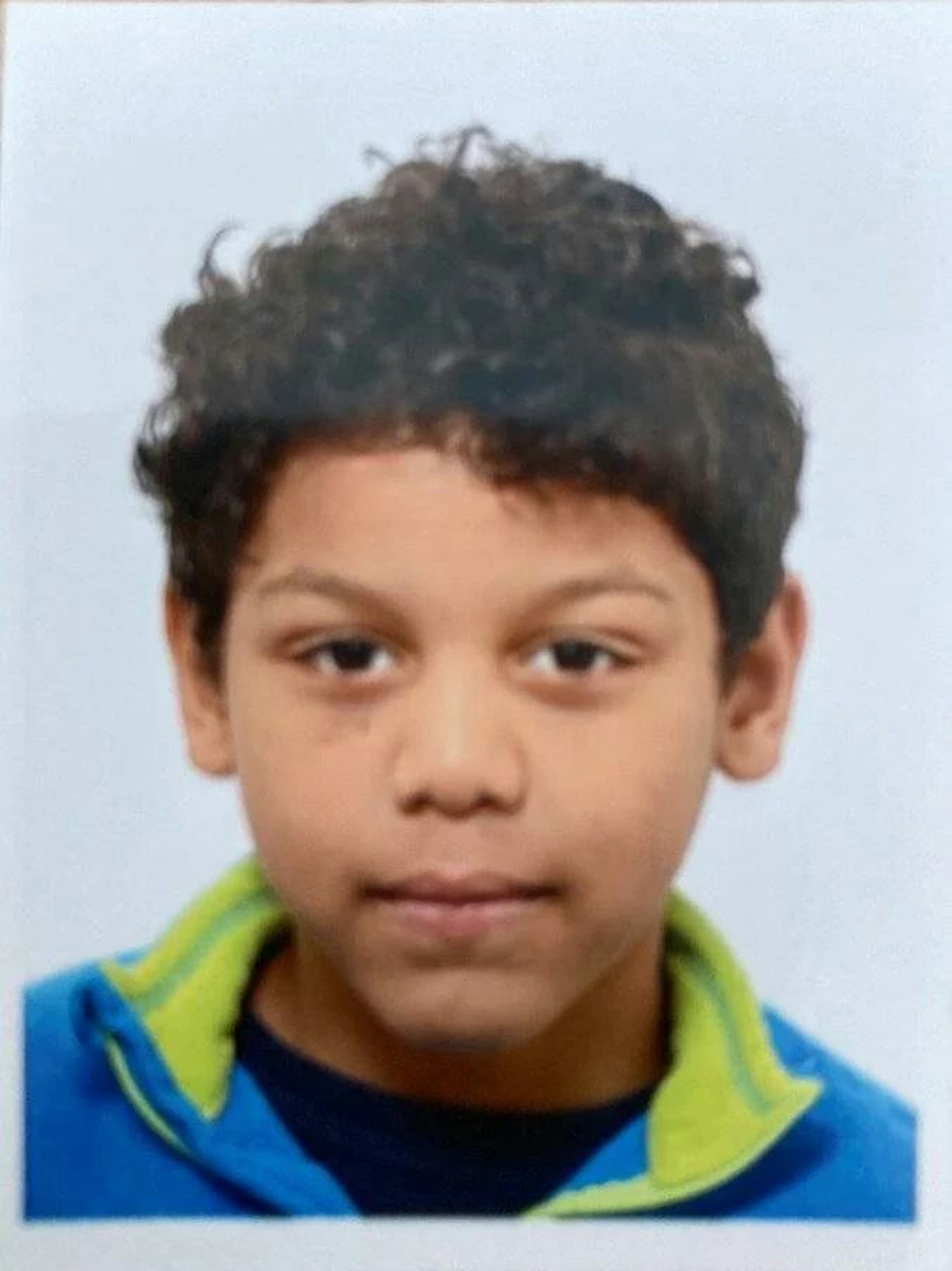 Das Foto eines Jungen mit dunklem Teint und dunklen, lockigen Haaren.