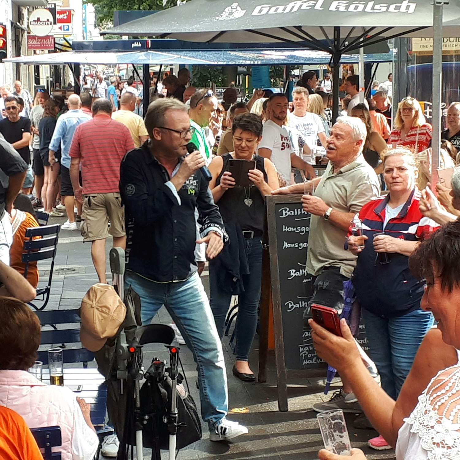 Ein Mann singt zwischen Menschen bei Sonnenschein.