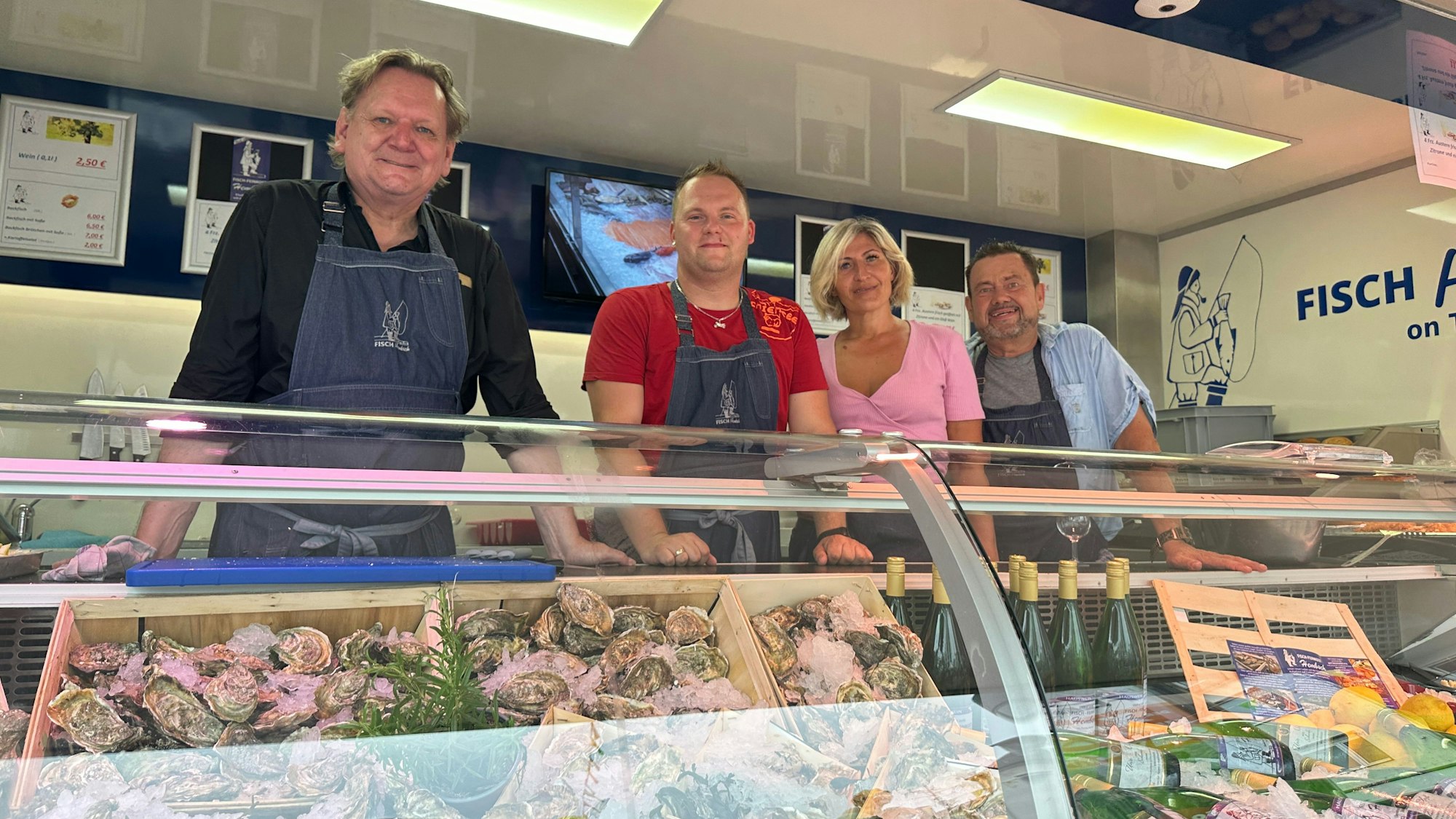 Vier Menschen hinter einer Theke, die mit Austern bestückt ist.