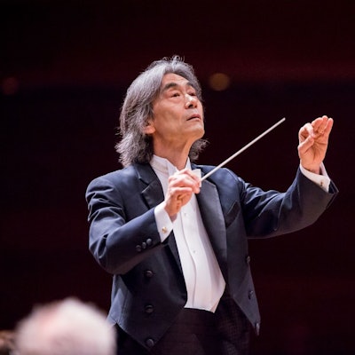 Kent Nagano dirigiert ein Orchester und trägt dabei einen Frack.