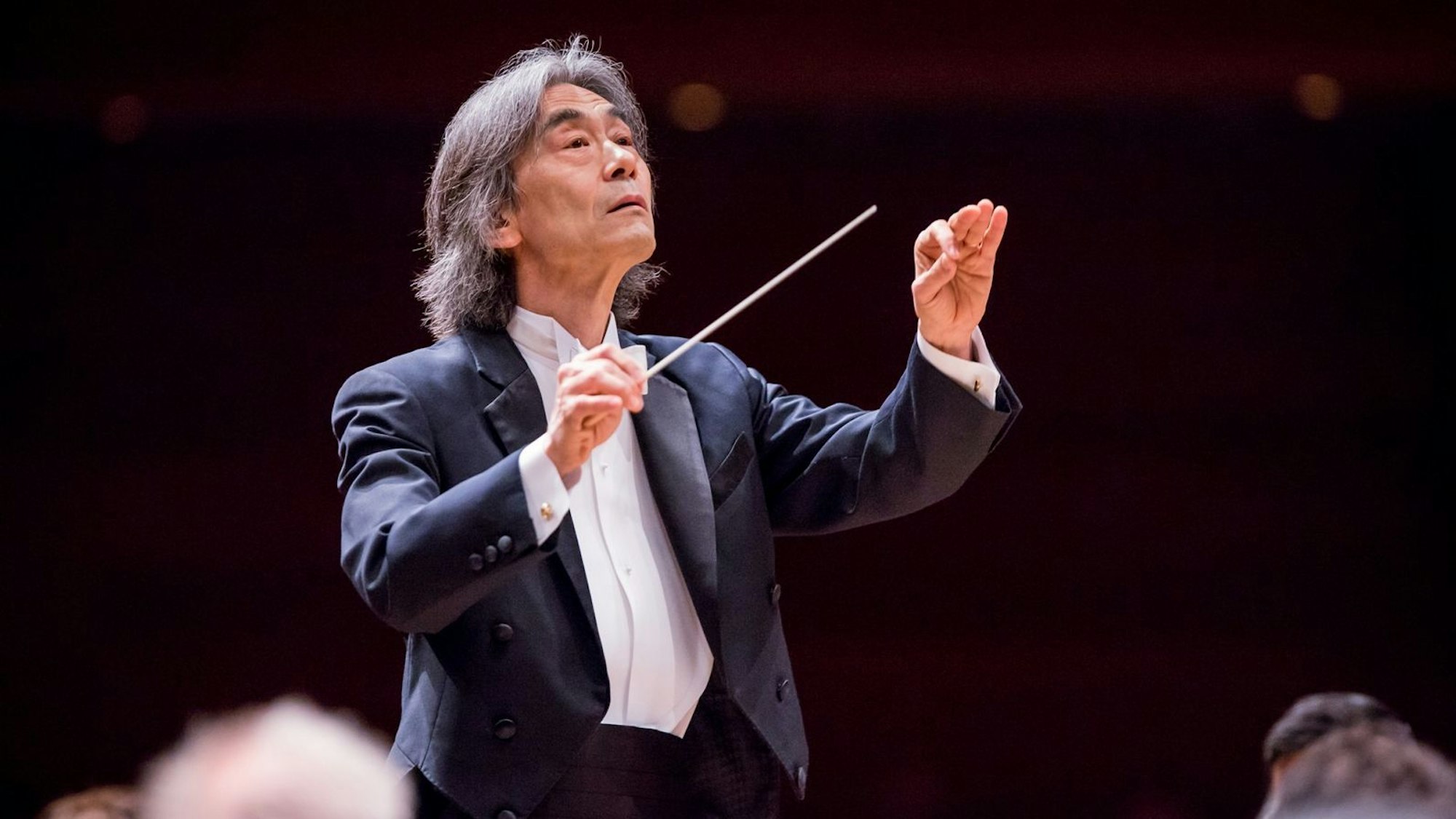 Kent Nagano dirigiert ein Orchester und trägt dabei einen Frack.