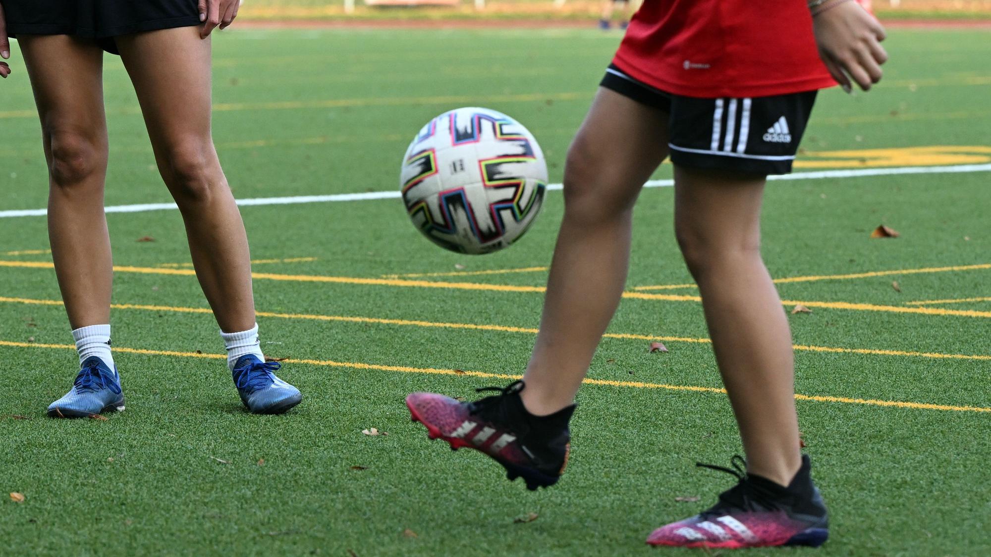 Ein Mädchen jongliert mit einem Fußball auf einem Fußballplatz.