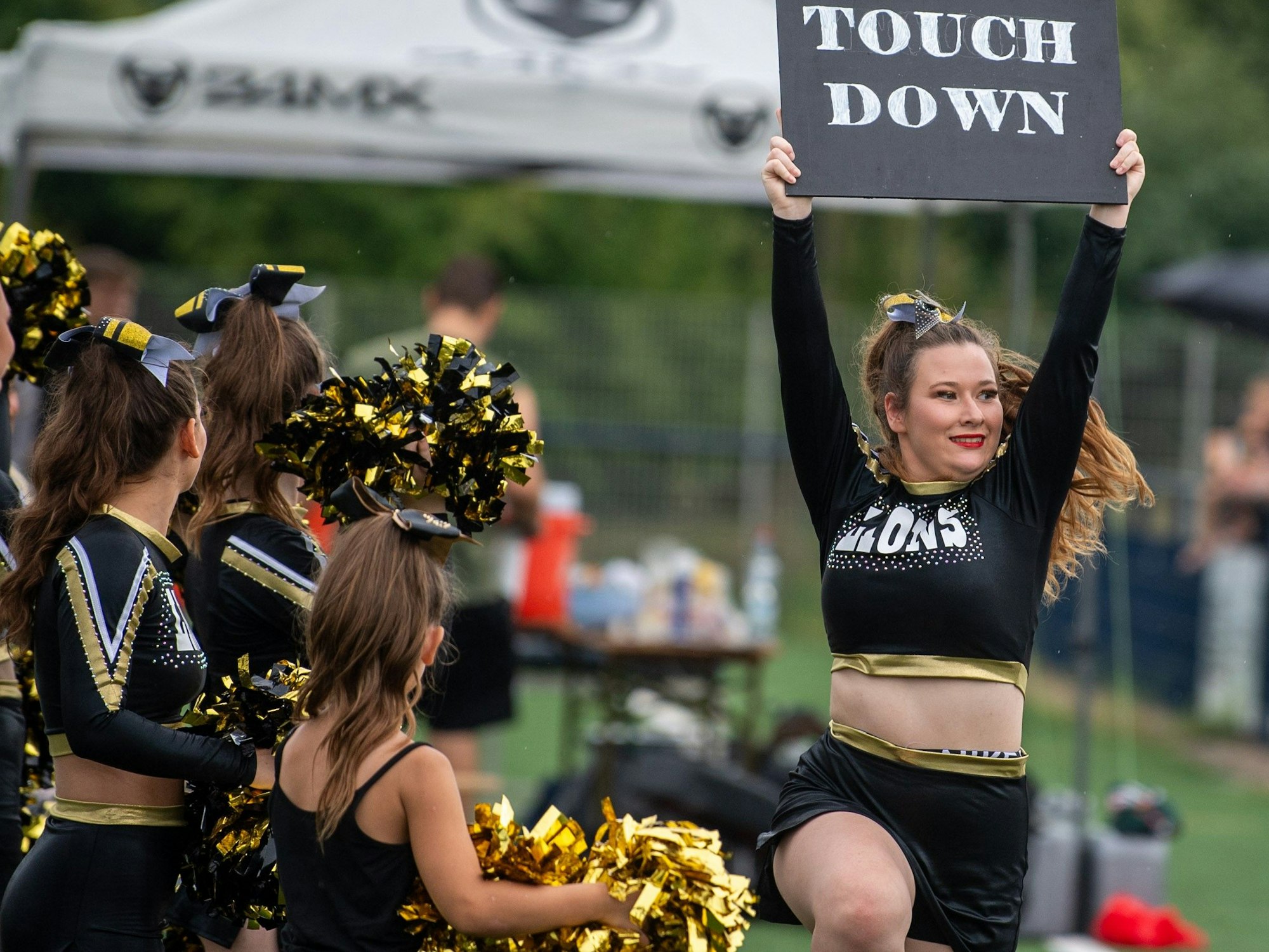 Eine Cheerleaderin zeigt mit einem Schild einen Touchdown an.
