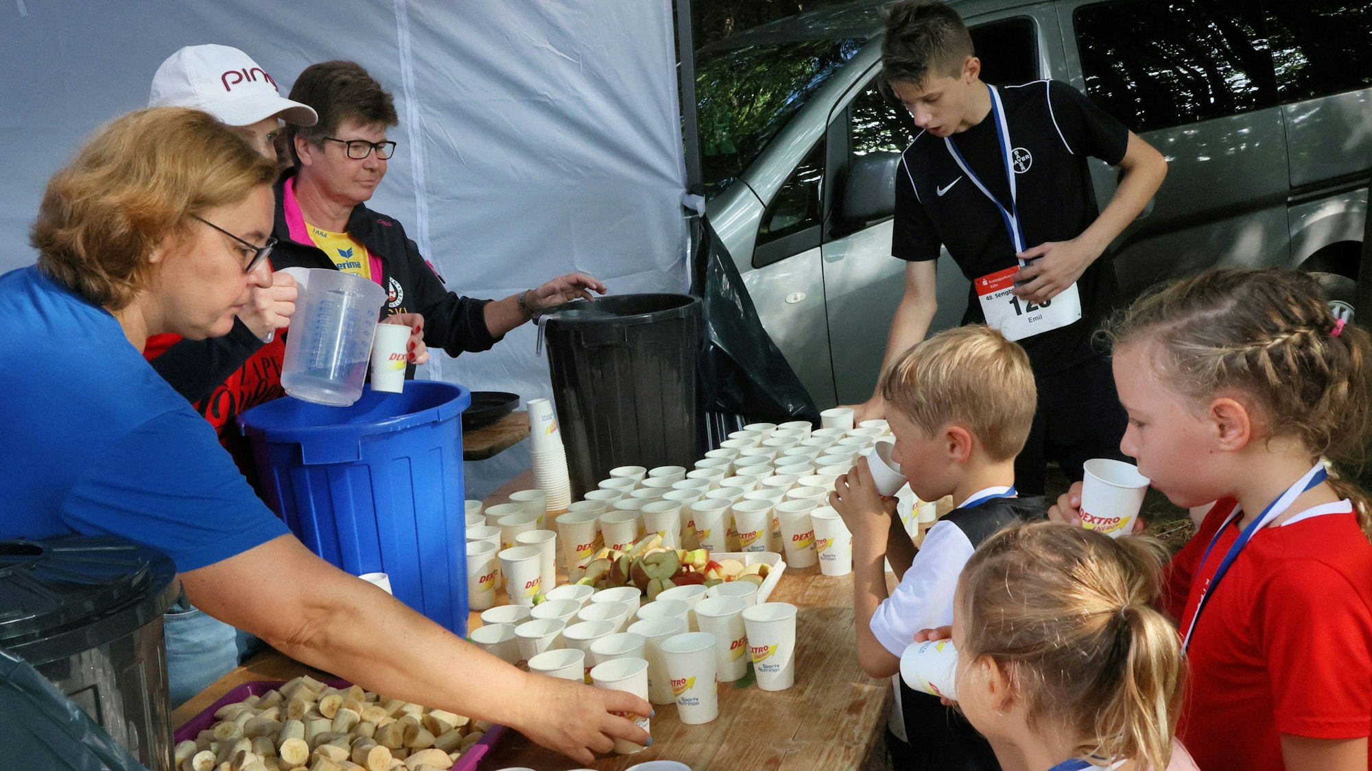 Kinder trinken an einer Erfrischungsstation.