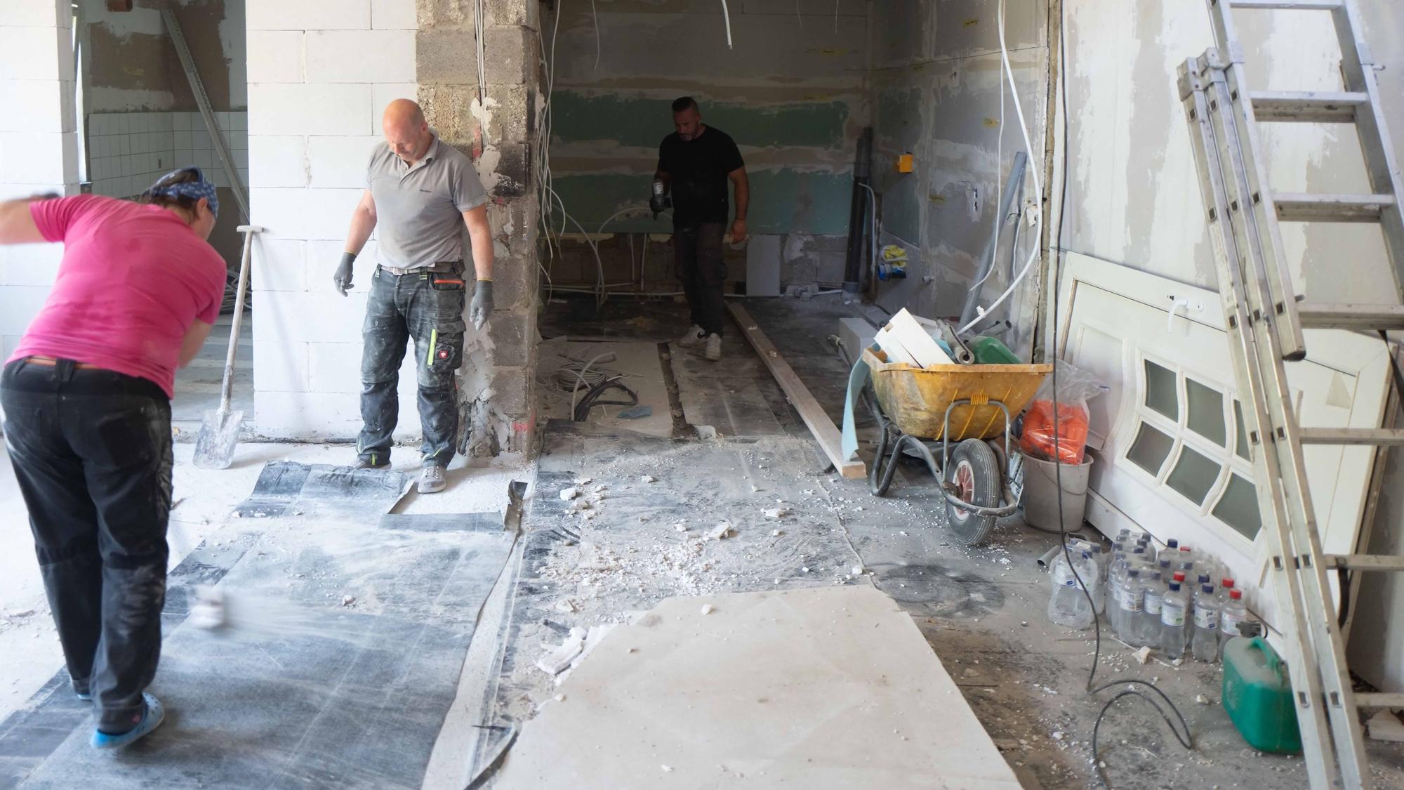 Das Bild zeigt zwei Helfer bei der Arbeit. Sie stehen im Rohbau des Hauses.