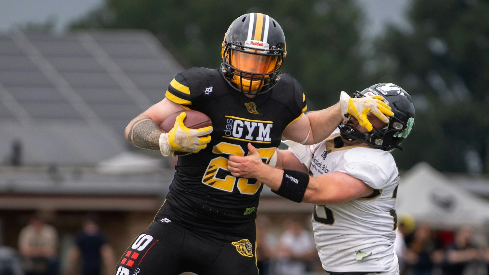 Zweikampf zwischen zwei Football-Spielern. Der ballführende Spieler greift dem Gegner ins Gesicht.