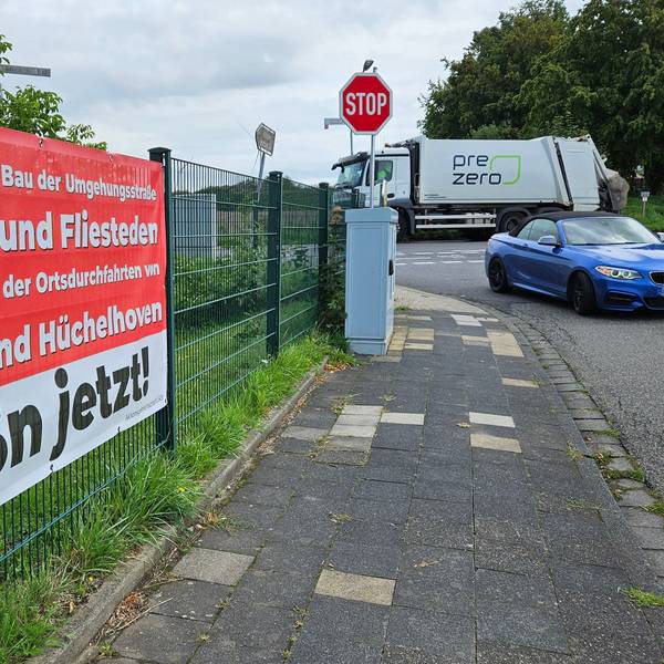 Auf einem Plakat in Rheidt-Hüchelhoven wird der Bau der Ortsumgehung für Pulheim, Fliesteden und Büsdorf, der L93n, gefordert.