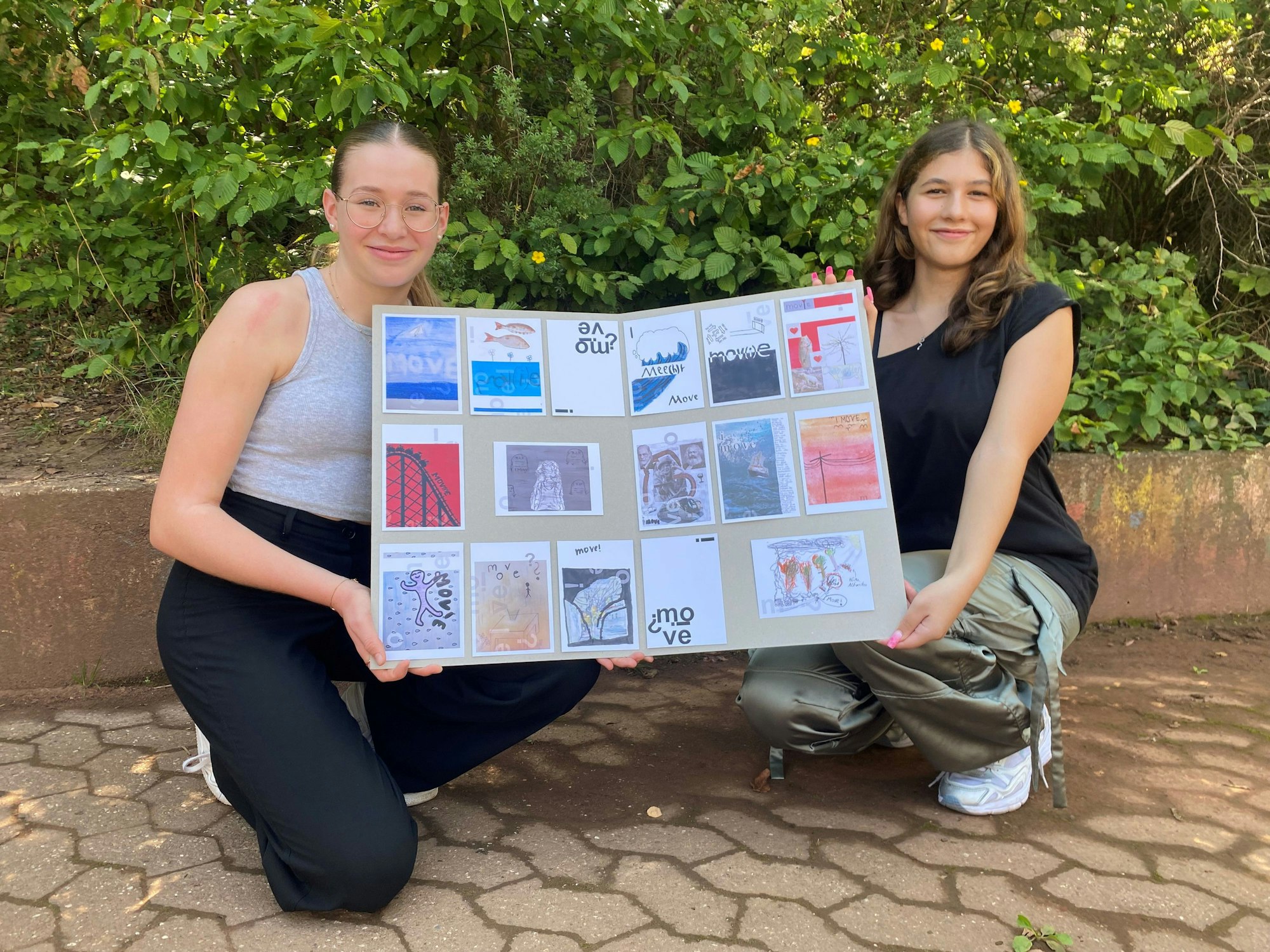 Die Schülerinnen Luisa Flaschentreher (l.) und Leila Razk halten ein Plakat hoch, darauf kleben verschiedenen Postkarten