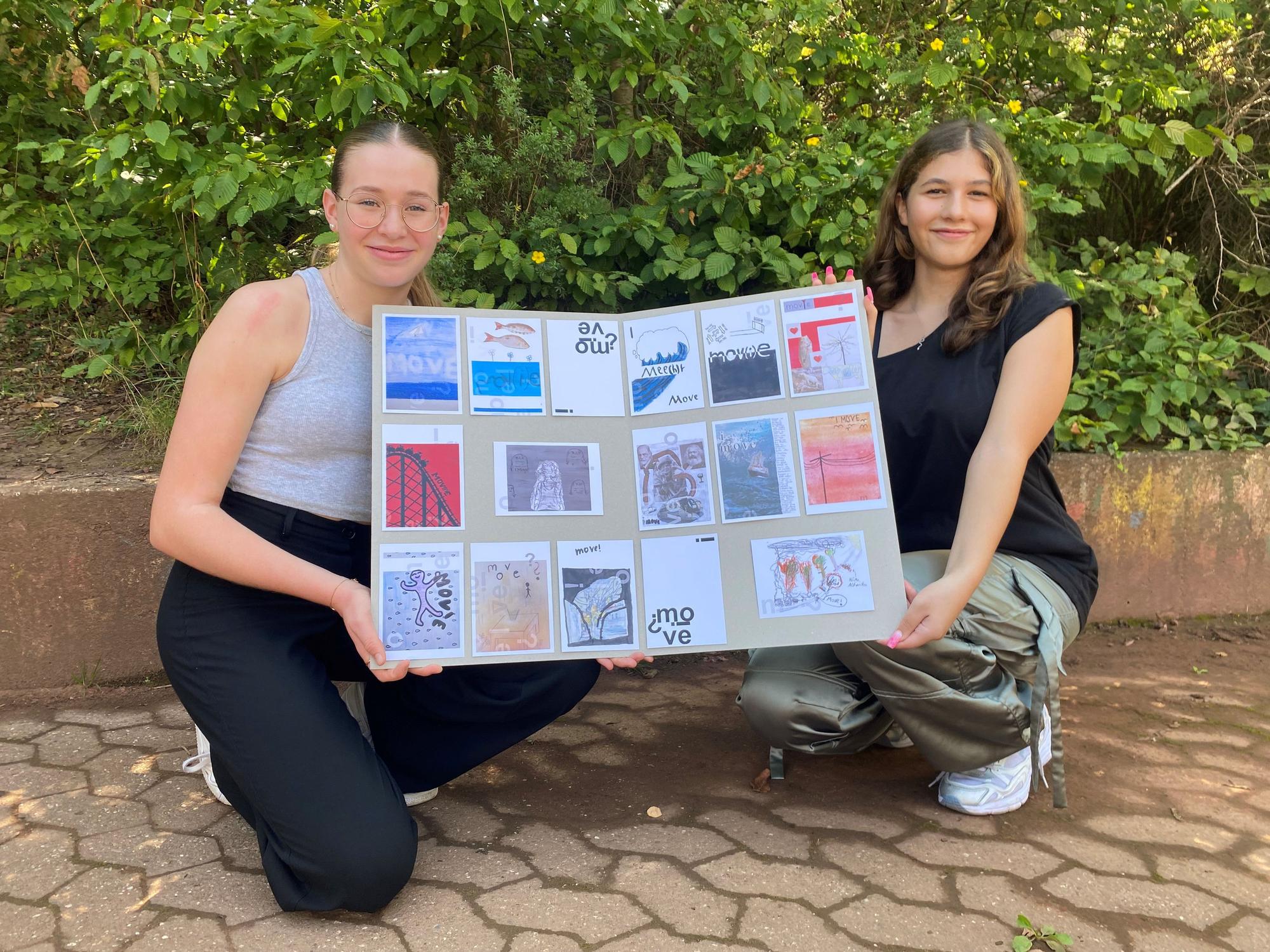 Die Schülerinnen Luisa Flaschentreher (l.) und Leila Razk halten ein Plakat hoch, darauf kleben verschiedenen Postkarten