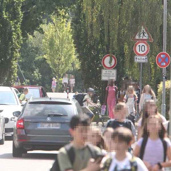 Schulkinder und Autos in einer schmalen Wohnstraße