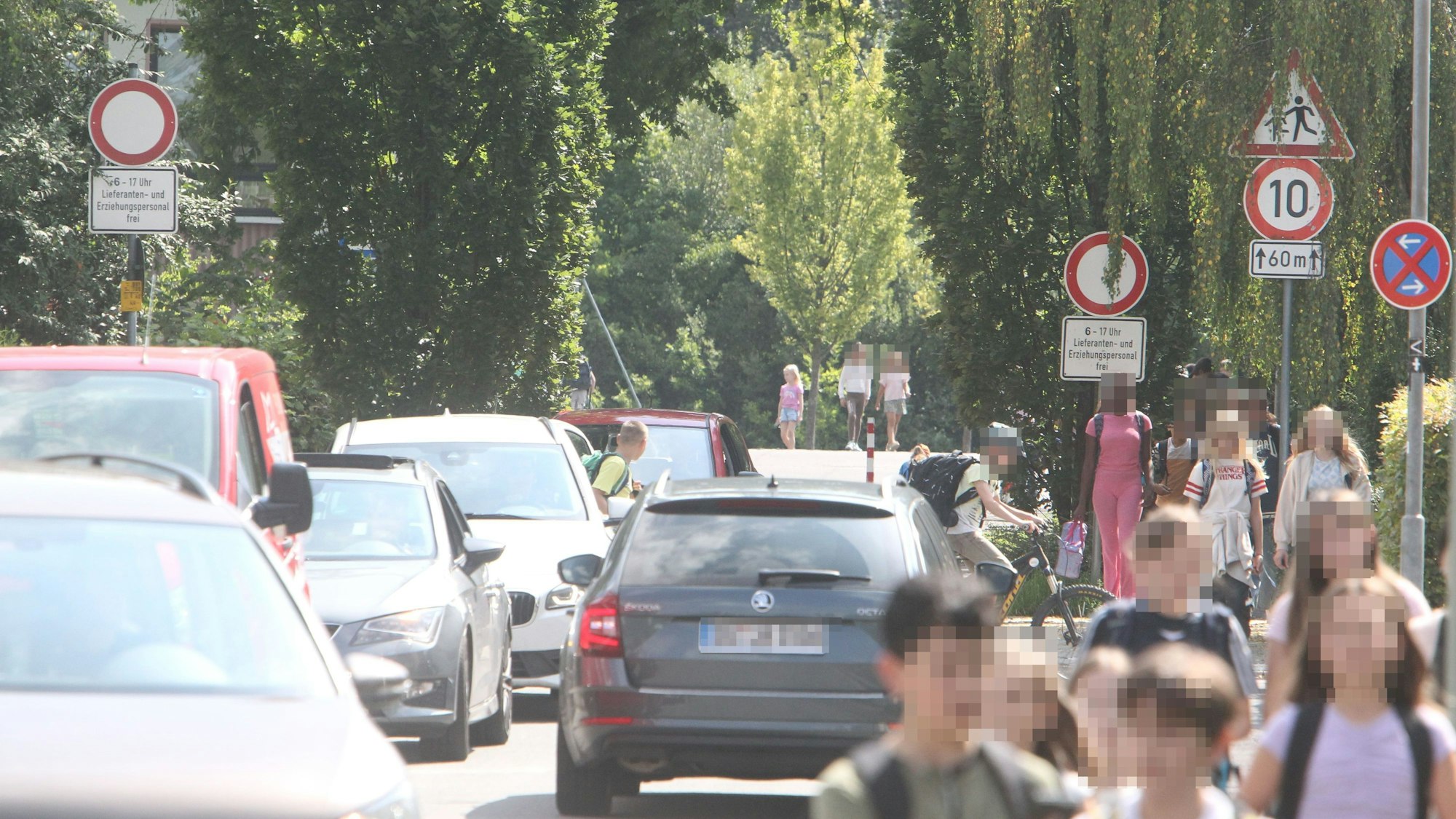 Schulkinder und Autos in einer schmalen Wohnstraße
