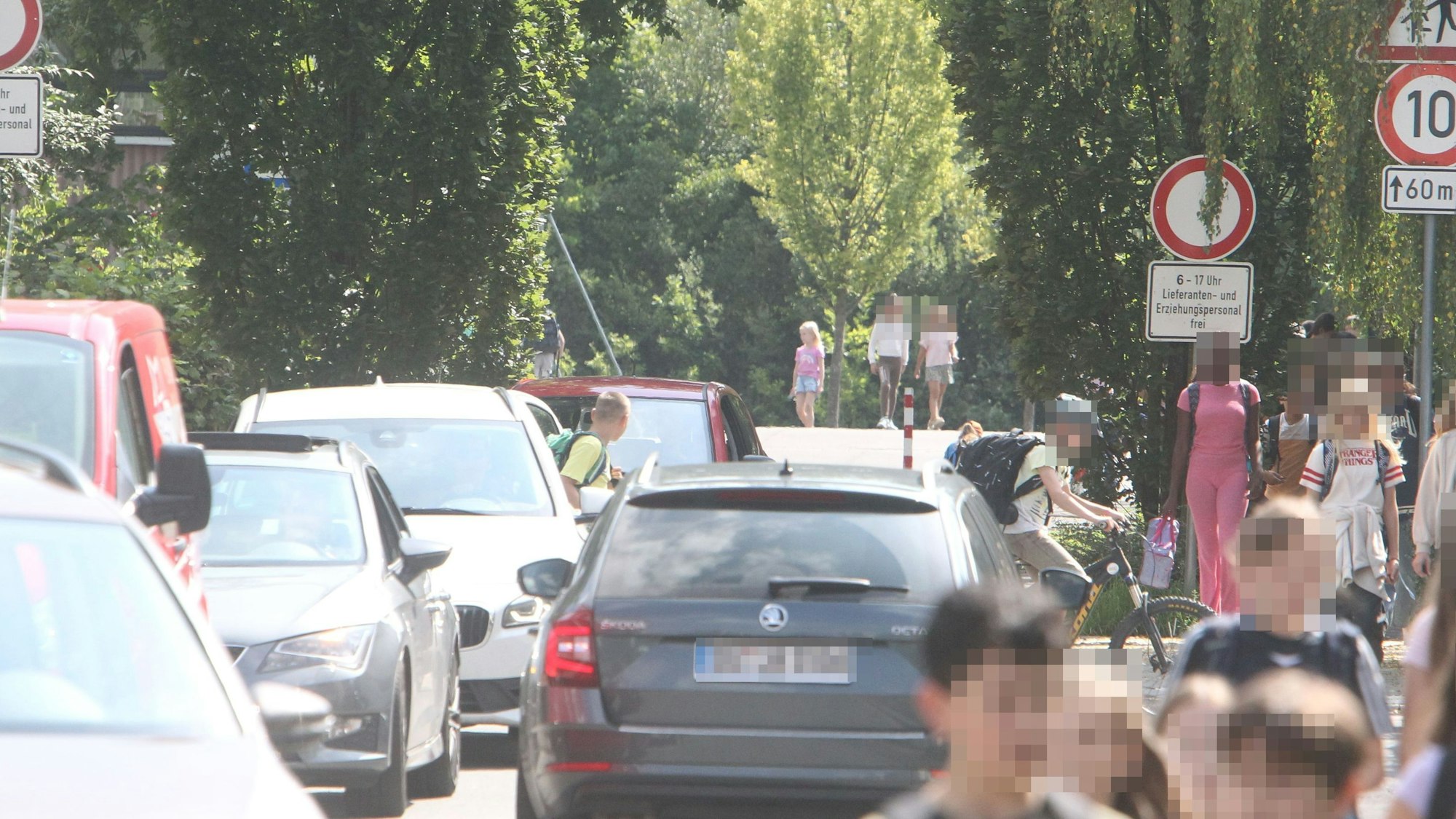 Autos und Schulkinder in einer schmalen Straße