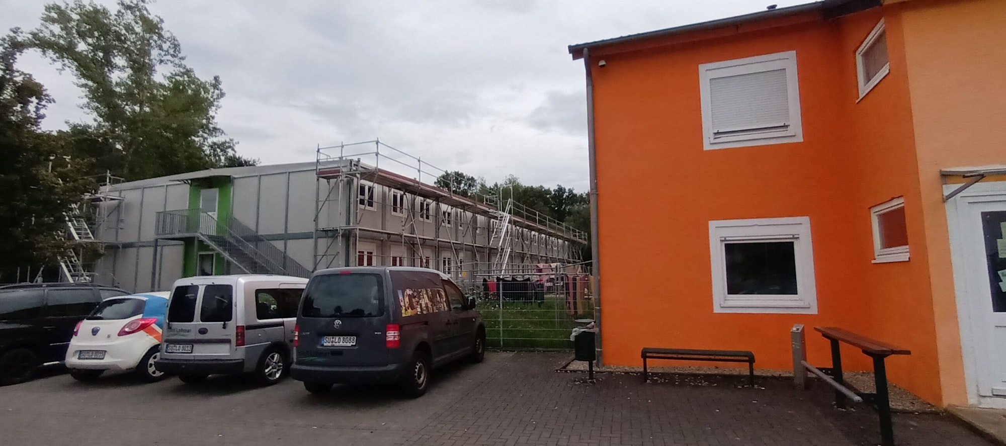 Eingerüstete Container neben einem Wohn- und Bürogebäude.