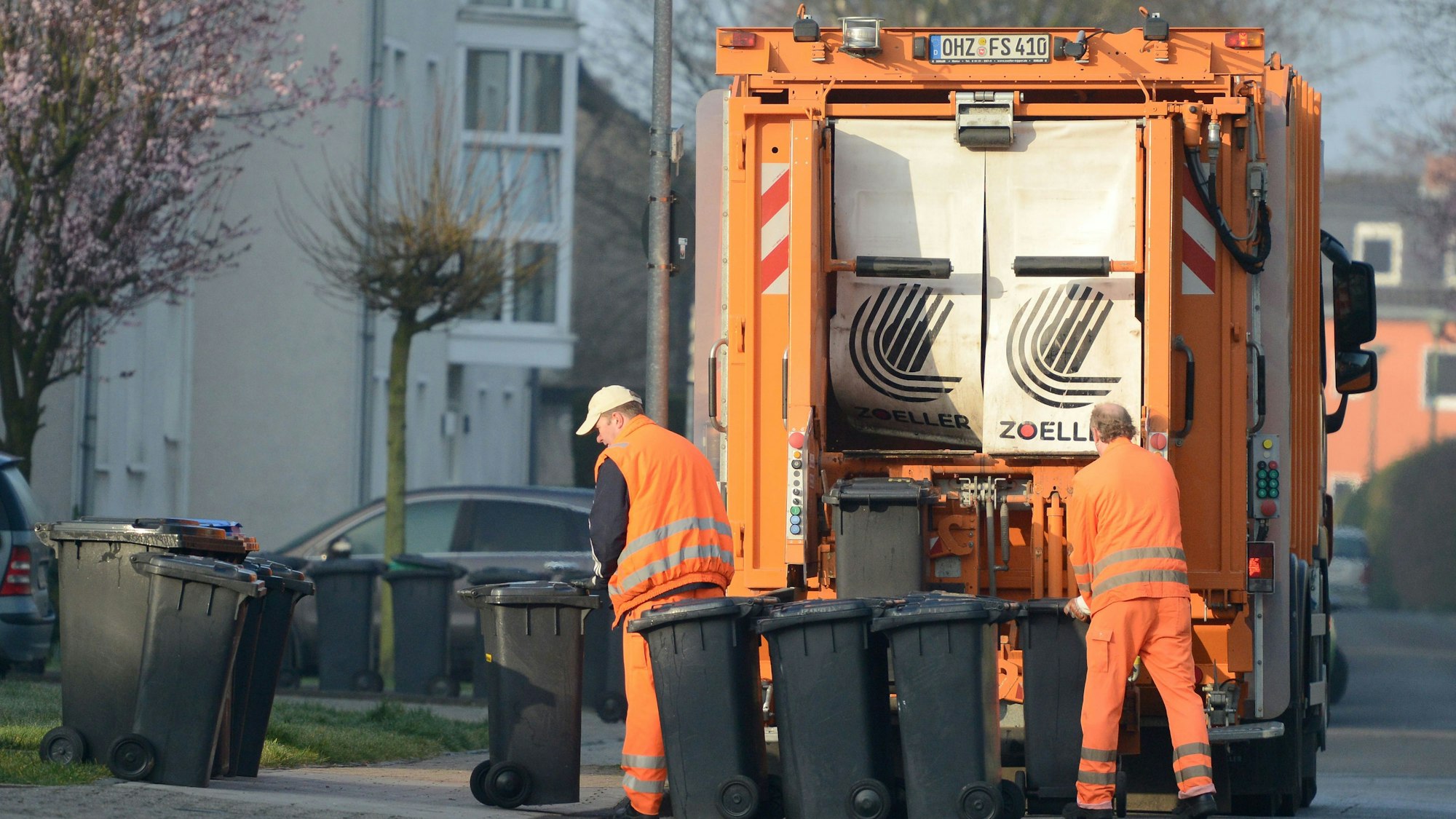 Abtransport von grauen Mülltonnen durch die Müllabfuhr.