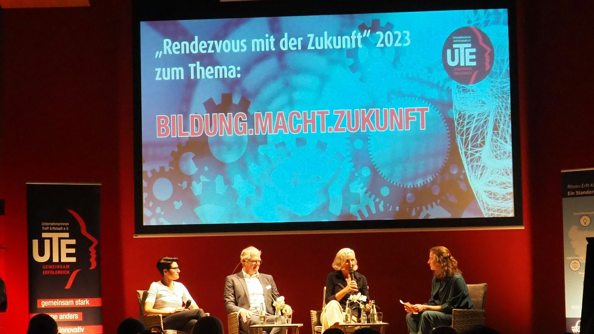 Vier Menschen sitzen im Halbkreis auf einer Bühne.