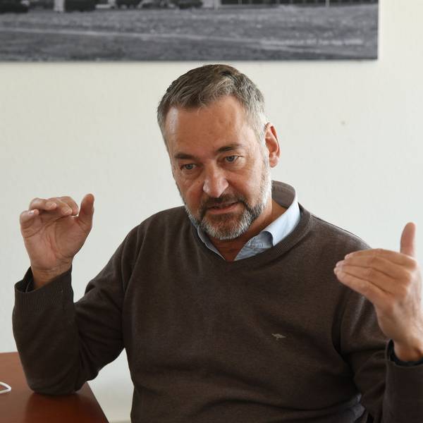 Hein Mulders trägt einen Pulli und darunter ein Hemd. Er hat einen grau melierten Bart und dunkelgraue Haare.