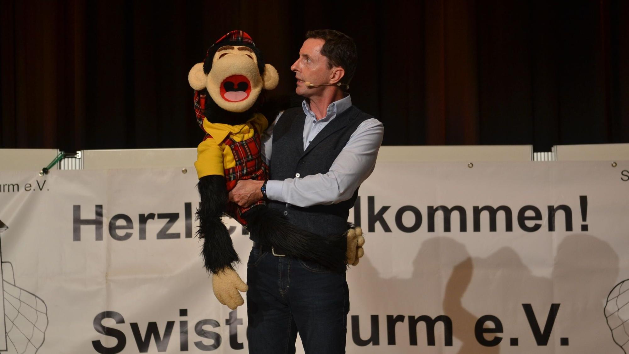 Der Bauchredner Klaus Rupprecht hält bei einem Auftritt in Weilerswist seinen „Partner“, einen Plüsch-Affen, im Arm.