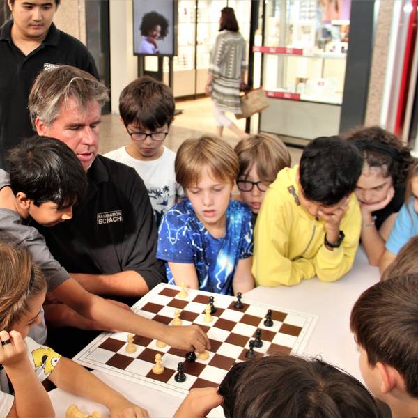 Der Profi Sebastian Siebrecht spielt Schach, um ihn herum stehen viele Kinder.