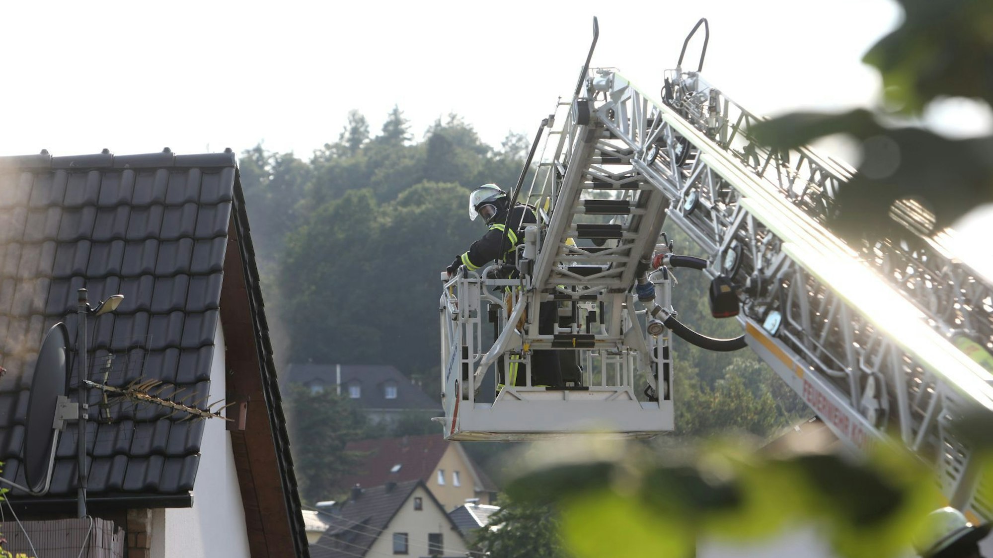 Ein Feuerwehrmitglied mit Atemschutz steht im Korb der ausgefahrenen Drehleiter.
