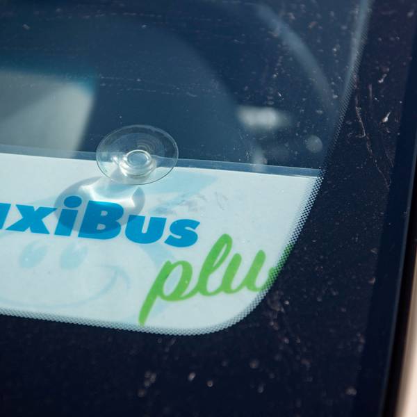 Das Bild zeigt ein Schild in einem Taxi, das kenntlich macht, dass es sich um einen TaxiBus handelt.