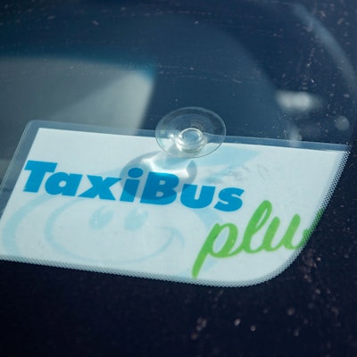 Das Bild zeigt ein Schild in einem Taxi, das kenntlich macht, dass es sich um einen TaxiBus handelt.