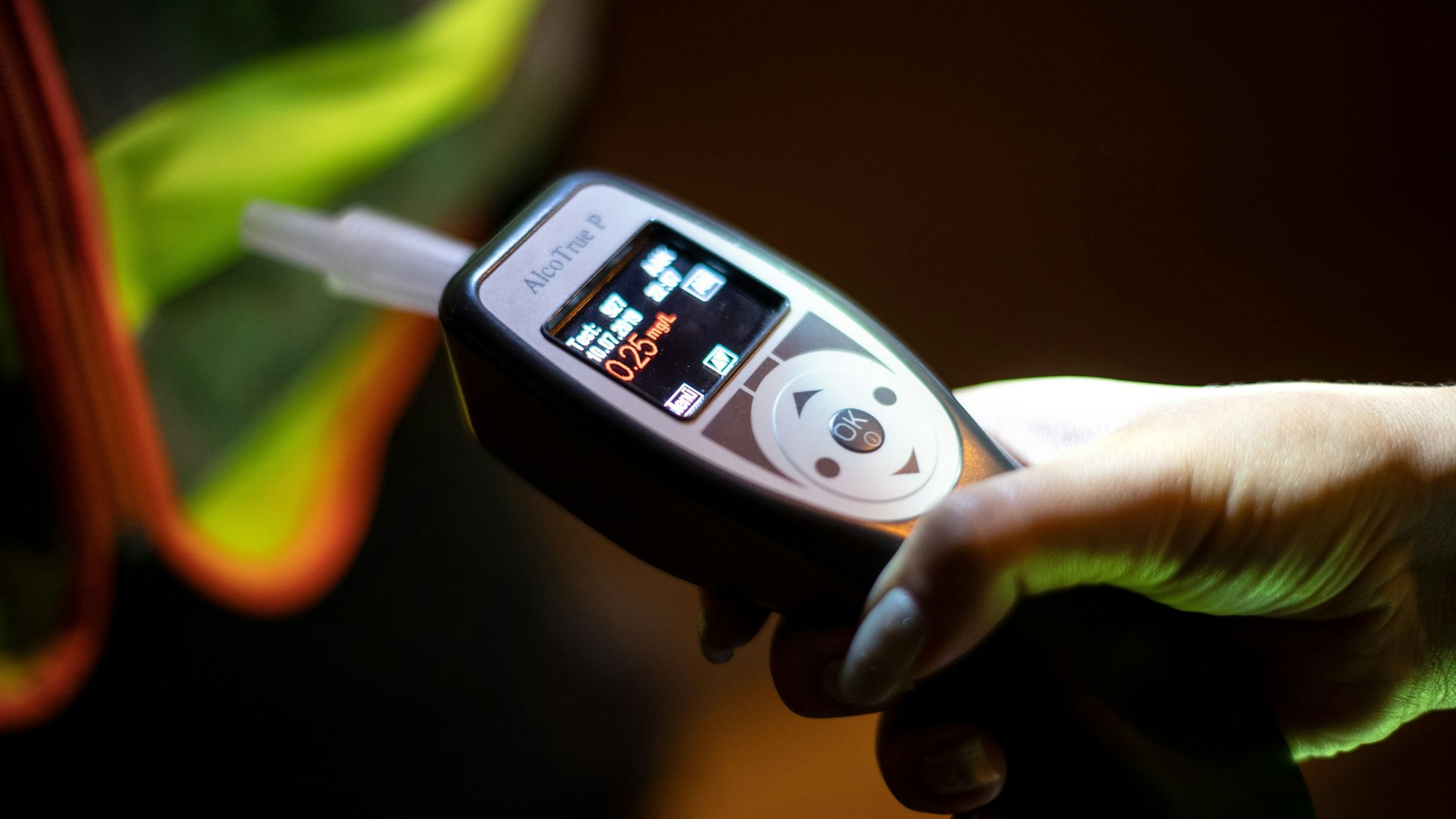 Eine Polizistin kontrolliert mit einem Atemalkoholtest einen Fahrer bei einer Verkehrskontrolle. Das Bild zeigt eine Hand, die das Testgerät festhält.