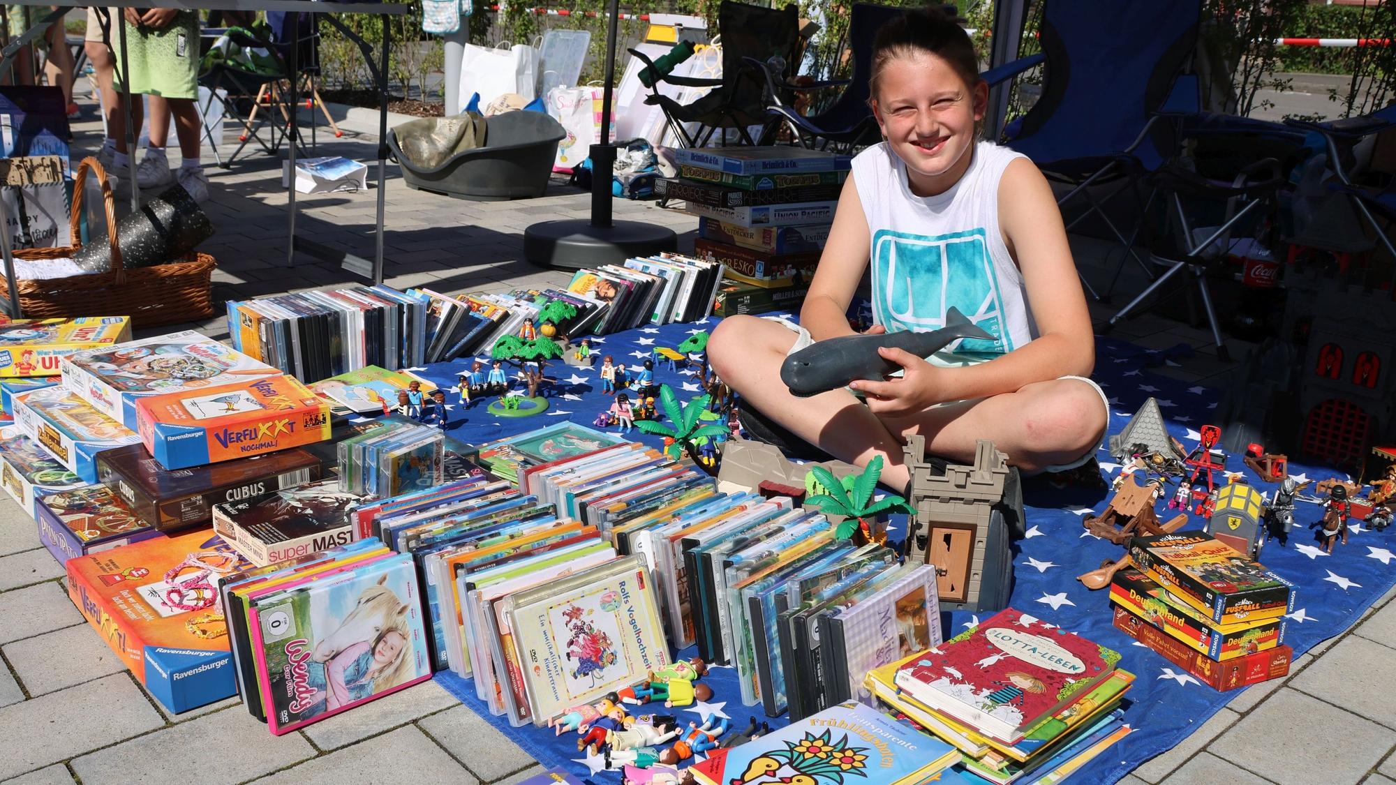 Der Junge Leon Schöffler sitzt auf seiner Verkaufsdecke inmitten vieler Spielsachen und Bücher.