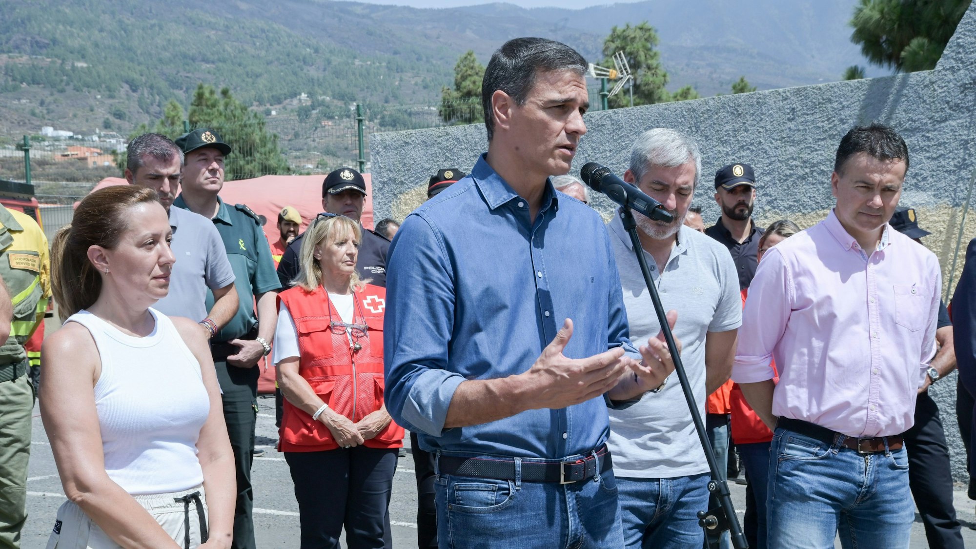 Mehrere Personen stehen vor Menschen in Arbeitskleidung auf der Insel Teneriffa.