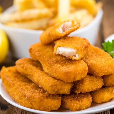 Fischstäbchen liegen angerichtet auf einem Teller.